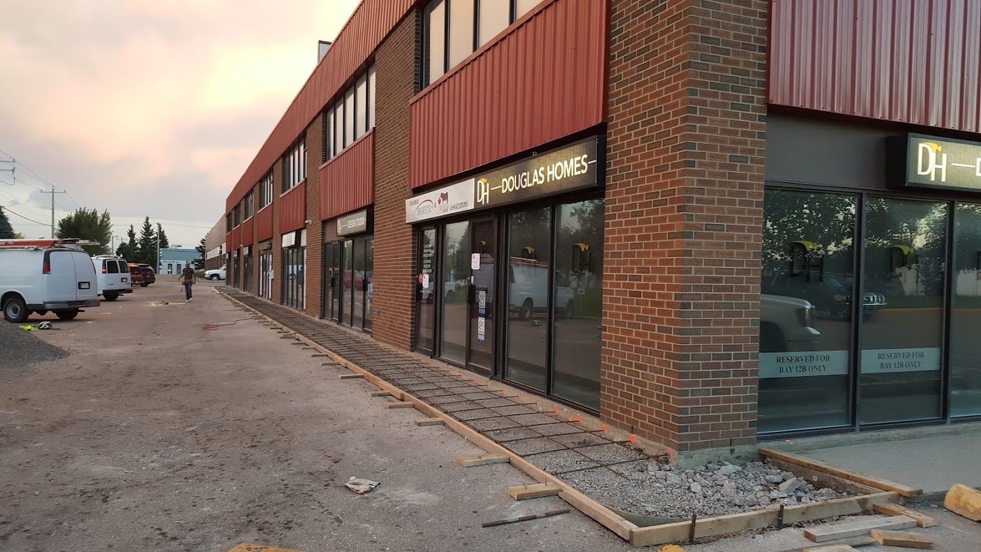 Sidewalk formwork and gravel base along a commercial building