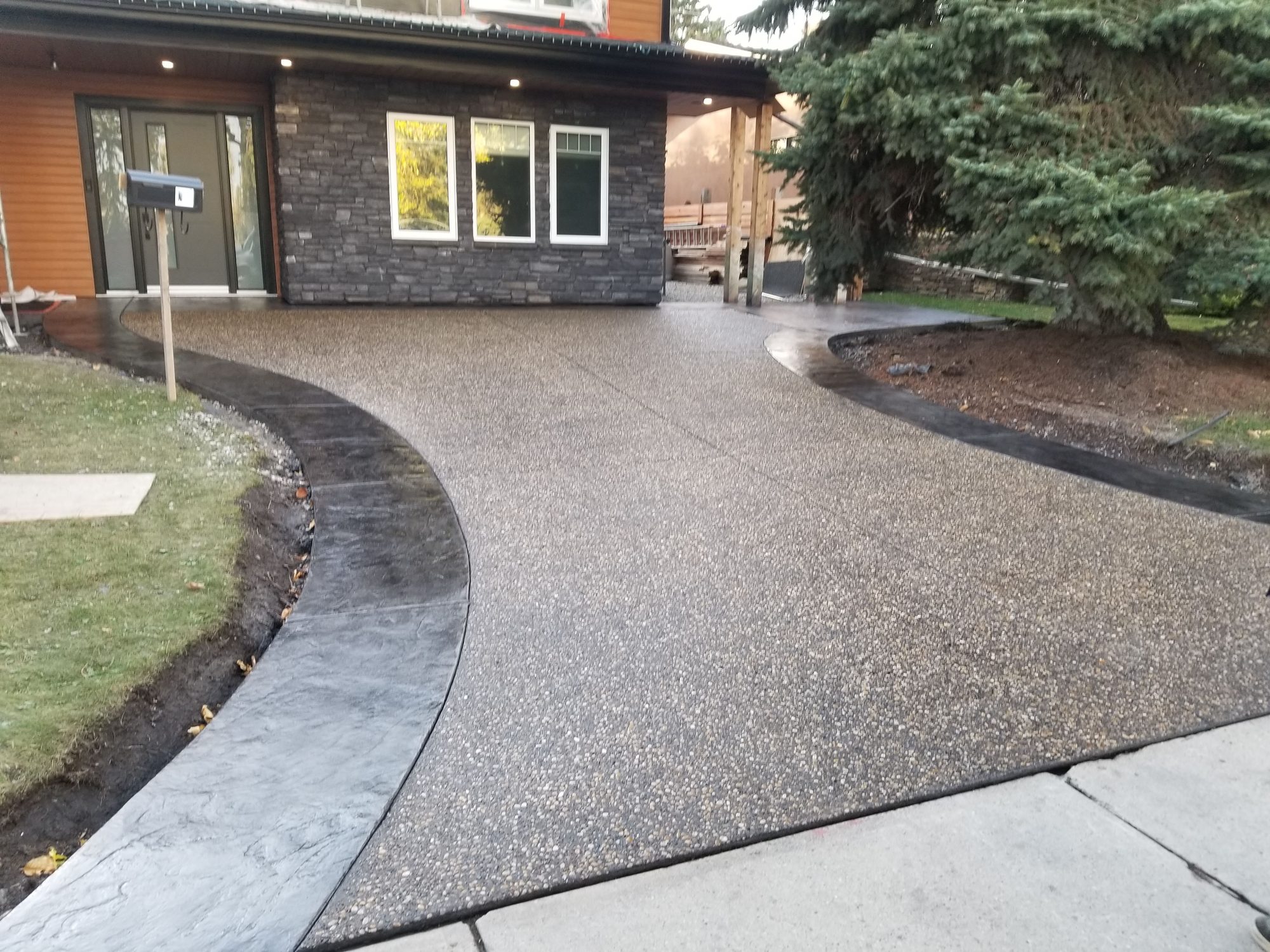 Exposed aggregate driveway with a dark stamped border curving in front of a Calgary-area home